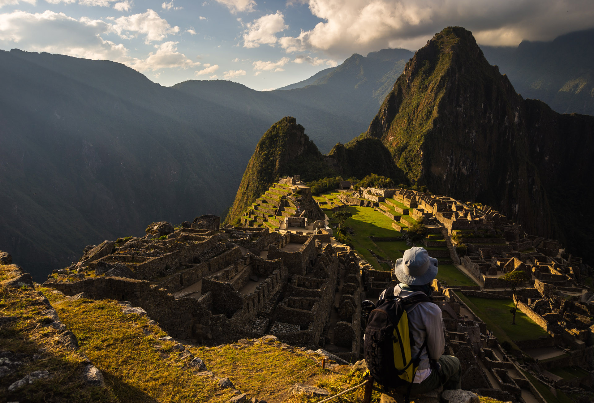 Machu Picchu illuminated by the last sunlight. The Inca's city is the most visited travel destination in Peru. One person sitting in contemplation.